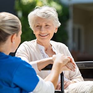 A nurse tends to a woman sat in a wheel chair