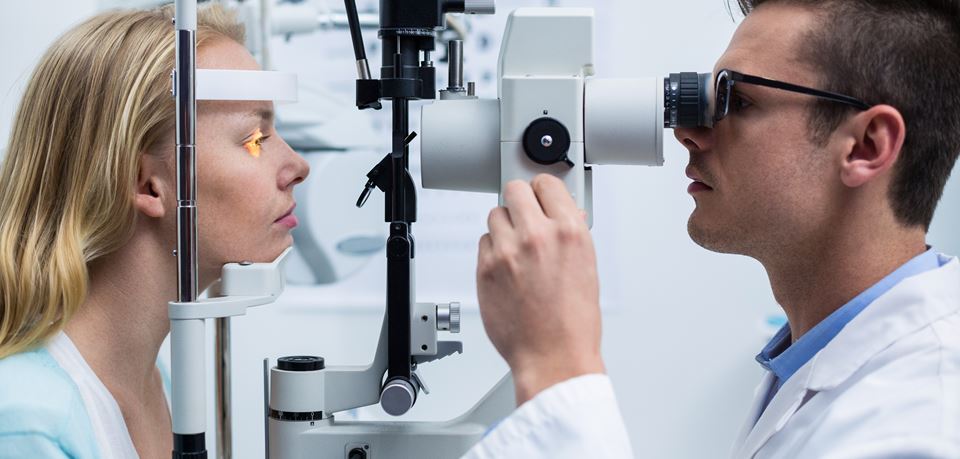 An opthalmologist tests a patient's eyes with a machine